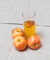 Glass of apple juice and fresh apples near on table.