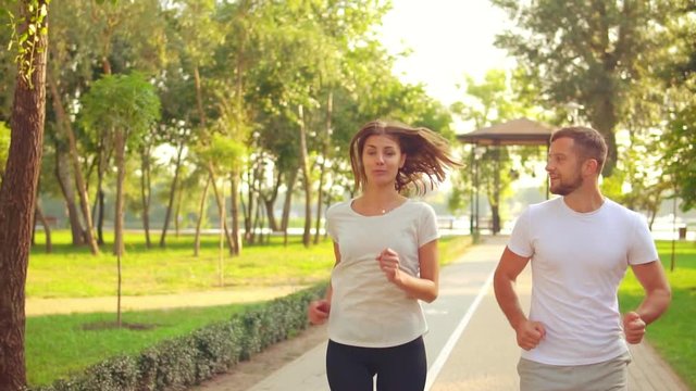 happy fitness couple training together in the morning in city park healthy lifestyle young friends jogging and talking