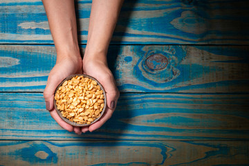 Brunette model holding pot of ceramic with soy toast, blue wooden background.