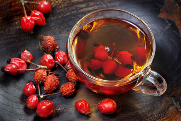 dog rose berries.dog rose tea. a cup of curative rosehip tea on a wooden table. vitamin tea. remedy for cold and flu
