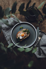 Fototapeta na wymiar Ham and Fried Quail Egg Toast with Mustard and Basil on a dark wooden background, top view