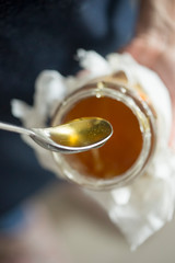 Honey in jar spoon, hands