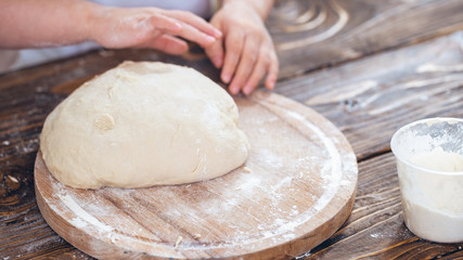 dough in the hands of a child, a wooden table.