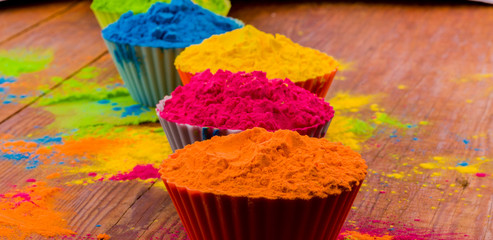 Obraz premium Happy Holi greeting card designed showing Indian traditional sweet and salty food, flowers and powder colours arranged over white background or clay