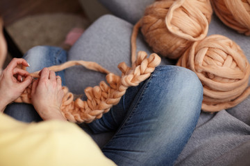 The process of knitting blankets made of Merino. blanket made of natural sheep wool. hand yarn close-up. home produces handmade plaid. designer volumetric blanket. loop weaving knits with bare hands