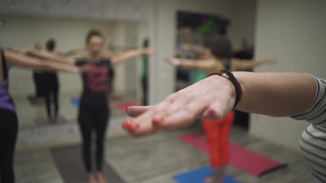 close view group of young women does wrist extension and stretching exercises standing on carrymats at yoga class