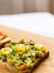Open sandvich with guacamole, yellow tomato cherry and dill on wood texture  background