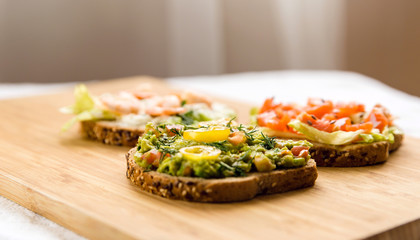 Open sandviches with guacamole, fish and prawn on wood texture  background