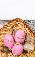 Copy space Easter pink eggs in a wicker on pink paper and knitted fabric background