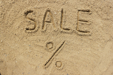 Sale word written on the sand at the beach, natural background