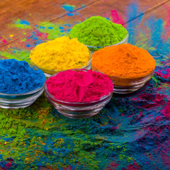 Bright colourful powdered pigments in glass bottles for Indian holi festival on dark slate...