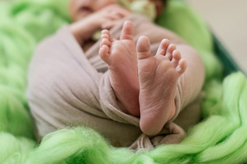 Feet of a newborn baby, toes  of a child, the first days of life after birth, green background, funny spread fingers