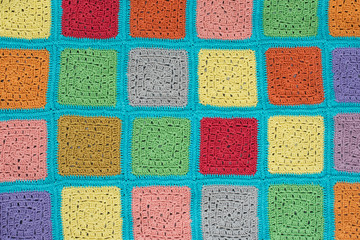  crocheted  lace tablecloth of multicolored squares ornament on a gray background, top view, place for text, natural wool