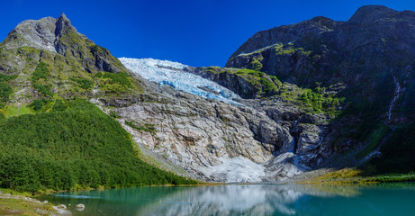 Norwegian landscape with milky blue glacier lake, glacier and green mountains. Norway