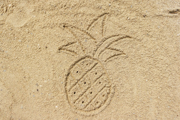 Drawing pineapple on the sand at the beach, natural background
