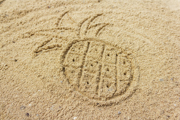 Fototapeta na wymiar Drawing pineapple on the sand at the beach, natural background