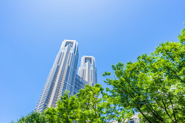 Obraz premium Asia Business concept for real estate, corporate construction and ecology - looking up view of panoramic modern city skyline with blue sky and green tree in shinjuku, tokyo, japan