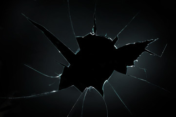 broken cracked glass with big hole over black background