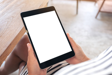 Mockup image of a woman sitting and holding black tablet pc with blank white desktop screen