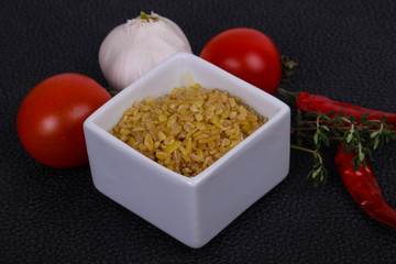 Raw bulgur in the bowl with tomatoes and garlic