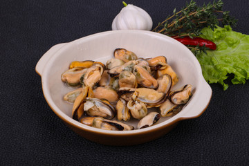 Pickled mussels in the bowl served pepper, garlic and salad