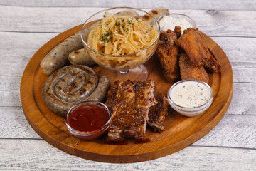 Meat plate with grilled sausages, ribs and chicken wings