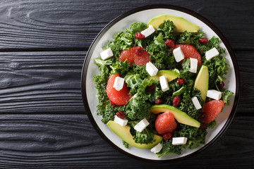 Fresh salad of kale, avocado, grapefruit, cheese and dried cranberries close-up on a plate. horizontal top view