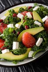 Fresh salad of kale, avocado, grapefruit, cheese and dried cranberries close-up on a plate. vertical