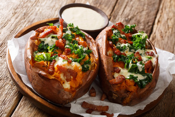 Homemade rich baked sweet potato with kale, bacon and cheese sauce close-up on a plate. horizontal