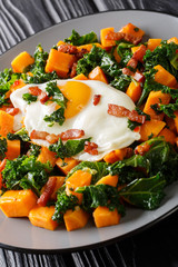 Roasted sweet potatoes with kale, bacon and eggs close-up. vertical