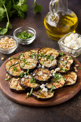 Fried eggplant with feta, pine nuts, fresh herbs (cilantro, parsley) and olive oil. Tasty vegetable snack, summer, spring food, picnic