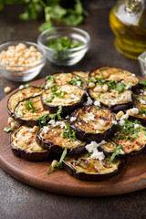 Fried eggplant with feta, pine nuts, fresh herbs (cilantro, parsley) and olive oil. Tasty vegetable snack, summer, spring food, picnic