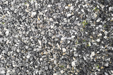 Top view of gray grit crushed stone texture ,The grass grows because there is a gap.