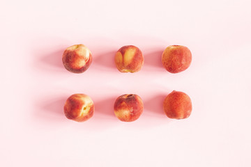 Peaches on pastel pink background. Flat lay, top view