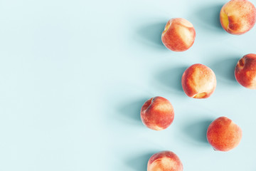 Peaches on pastel blue background. Frame made of fresh peaches. Flat lay, top view, copy space