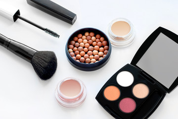 Set of decorative cosmetics on white background. Ball blush, cream eye shadow, palette of shadows, mascara, blush brush