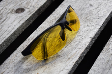 Safety yellow glasses on a wooden background. Glasses lie.