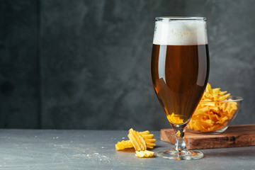 Glass of dark beer with bowl of beer snacks close up