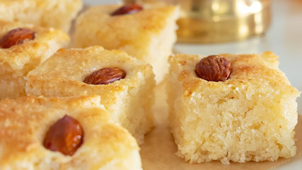 Close up pieces Basbousa or namoora traditional arabic semolina cake with almond nut and rose syrup. Selective focus.