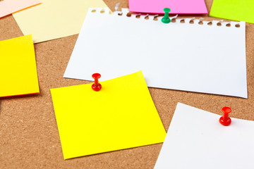 Cork board with several colorful blank notes with pins