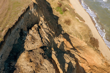 Fototapeta na wymiar Mountain landslide in an environmentally hazardous area. Large crack in ground, descent of large layers of dirt. Deadly danger at foot of landslide mountain. Soil erosion Avalanche. Steep coast, crack