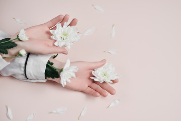 Creative image beautiful groomed woman's hands with white flowers with copy space on pink background in minimalist style. Concept template feminine blog, social media, beauty concept