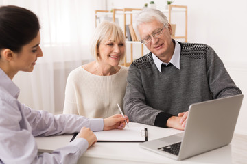 Fototapeta na wymiar Older couple considering new home purchase looking at laptop