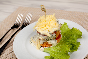 Sandwich with grilled meat tomato and cheese on a green leaf of lettuce.