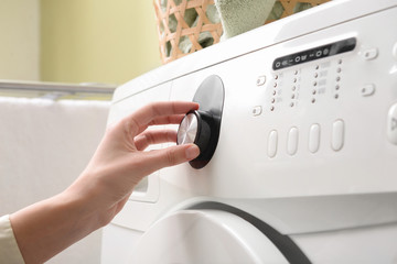 Woman switching on washing machine, closeup