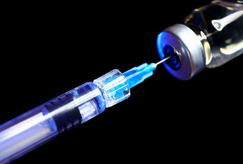 Syringe with filler for cosmetology and ampule on dark background