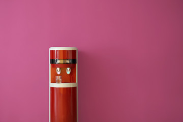 Modern water cooler on color background