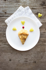 cake on a plate.  Creative idea for kid breakfast – pancakes with fruits and berries on a wooden background . Healthy and fun food for kids.