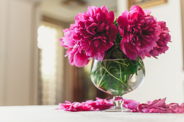 red peonies in glass vase stand on table