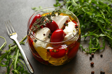 Glass jar with tasty feta cheese in olive oil on table